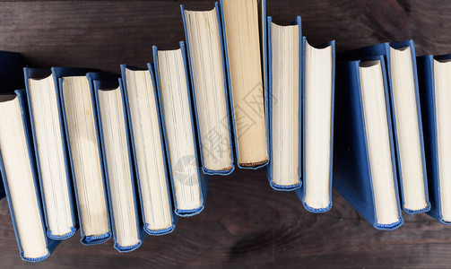 棕色木制桌顶视图上蓝色封面的堆叠书籍图片