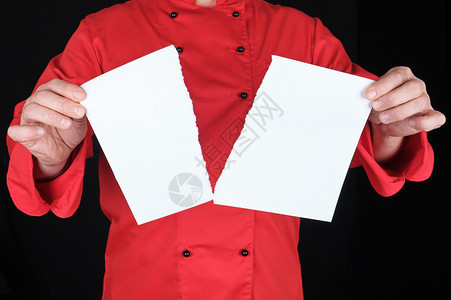 穿红色制服的男子拿着一张白色的纸片撕成两半黑色背景图片