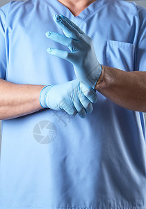穿蓝制服的医生戴上无菌乳胶手套关上图片