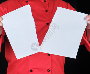 穿红色制服的男子拿着一张白色的纸片撕成两半黑色背景图片