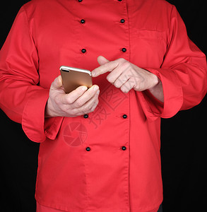 穿红制服的厨师手上握着黄色黑背景的智能手机图片