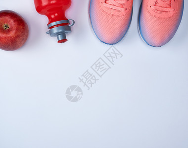 粉红运动鞋和白色背景的红水瓶最高视图图片
