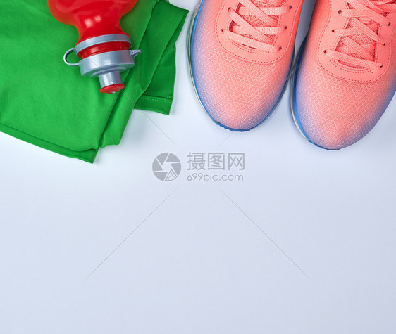 粉红运动鞋和白色背景的绿衣服复制空间图片