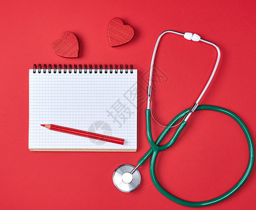 关于红色背景保健概念的开放空白笔记纸和绿色医学听诊器图片