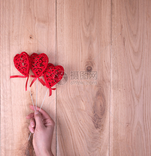 红色的心在人的手上黄色的橡木木板背景图片