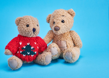 两只泰迪熊在蓝色背景上并肩坐在一起图片