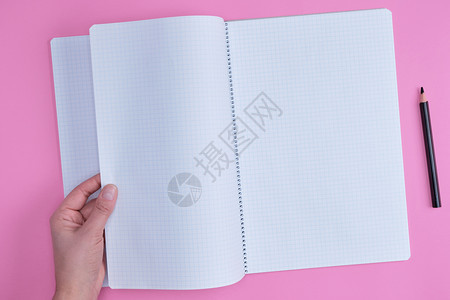 单元格中的空打开笔记本和女手粉红色背景顶视图图片