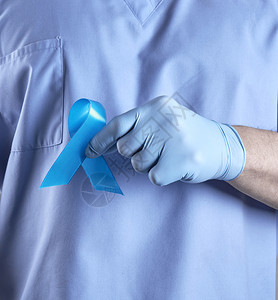 身穿制服和乳胶手套的医生上握着蓝丝带是前列腺癌抗治的象征图片