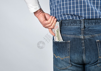 穿蓝色格衬衫和牛仔裤的男人在后口袋里放了纸币白色背景复制空间图片
