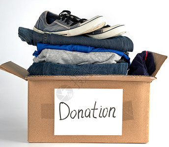 棕色纸盒中的折叠衣服和鞋子在白色背景上赠入帮助有需要的人概念图片