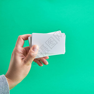 绿色背景复制空间的女手持白纸商业名片图片