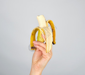 白底的雌手切开新鲜香蕉水果被咬掉背景图片