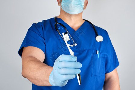 持有牙刷口腔卫生概念的无菌乳胶手套和蓝色制服的医生图片