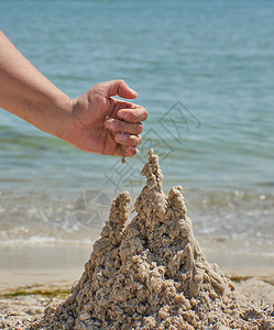 夏日用沙滩上的湿海建造一座城堡图片