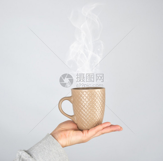 女手握着棕色陶瓷杯子喝着酒灰色的杯子冒出浓蒸汽图片