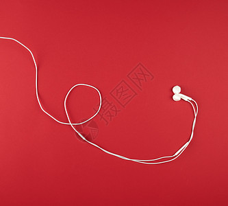 红色背景带白电缆的现代耳机图片