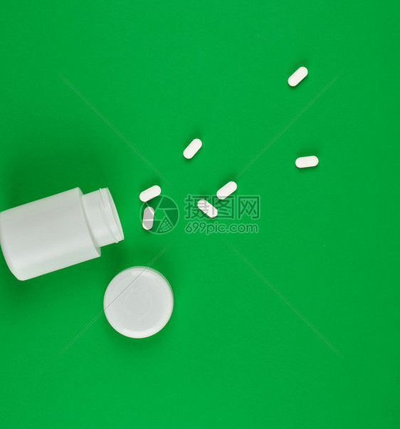 白色塑料罐头和分散在绿色背景顶视面的叶片图片