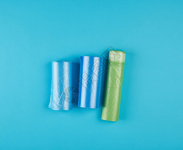 三卷装满塑料垃圾袋的卷子蓝色背景图片