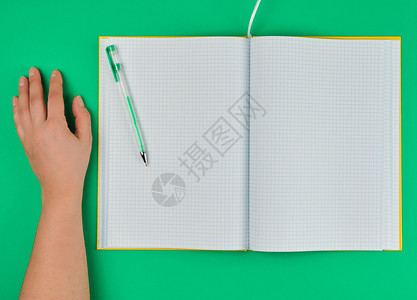 打开检查过的笔记本和女手顶视图绿色背景图片
