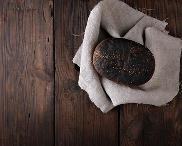 灰色纸巾上烤黑麦面包棕色木制桌顶视图复制空间图片