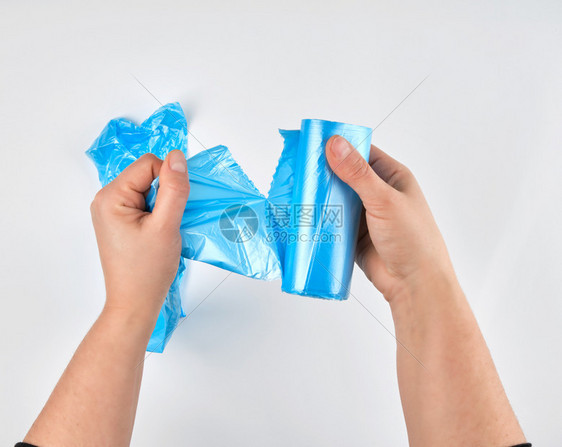 女用手从滚白背景顶视图中撕掉一个透明的蓝色包作为垃圾箱图片