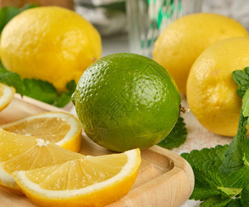 成熟的黄柠檬和石灰木板上的薄绿色柠檬或莫吉托的成分图片