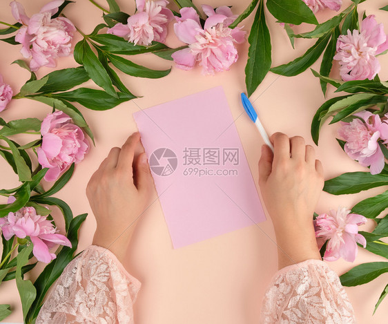 女手握着白笔在空的粉红色纸板上紧靠一束盛开的粉红色花朵束顶层风景图片