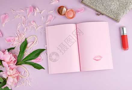 张开笔记本上面有白粉页一束花红口和紫色背景的女银离合器图片