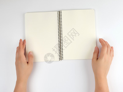两只手握着女持张开的笔记板在白背景顶视图上用干净的床单保存在白背景上图片