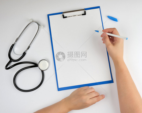 白空床单和背景的医学听诊器女手握笔用于撰写诊断或处方图片