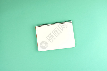 开张螺旋笔记本在绿色背景顶视图上用干净白纸打开笔记本图片
