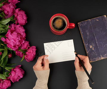 白明信片和两只女手桌子上有一束红面条花和一杯咖啡陶瓷最高风景图片