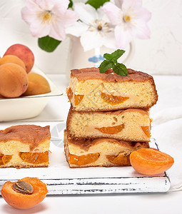 白木板上底面上鲜杏子的烤方块蛋糕海绵图片