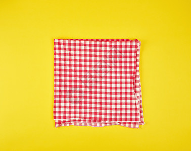 在一个黄色背景的笼中折叠成红色的厨房毛巾图片