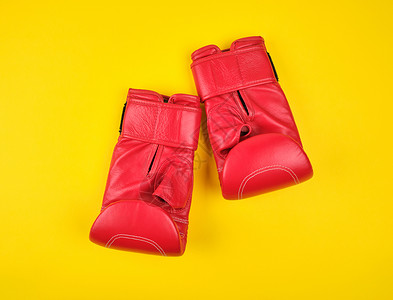 一对红色皮革拳击手套黄色背景平面背景图片