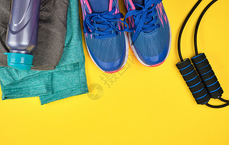 蓝色妇女运动鞋和健身服装黄色背景顶视复制空间平铺图片