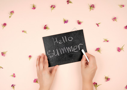 黑色粉笔框上面有刻着喜好夏天和两只女手上面有白色粉笔图片