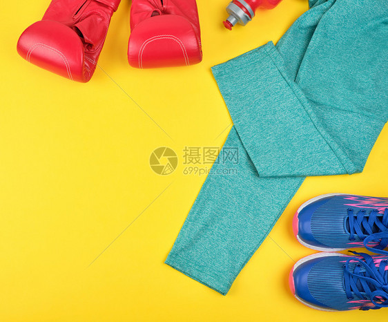 一对蓝色运动鞋红皮拳击手套和绿色衣服黄运动背景图片