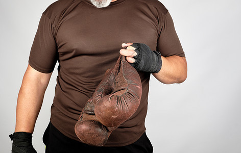 穿着棕色衣服的运动员带着非常古老的皮革拳击手套白底图片