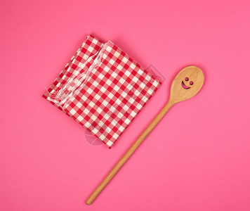 红厨房毛巾上刻面的木勺子粉红色背景复制空间图片