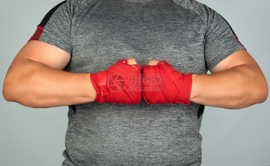 身着灰色衣服的运动员将双手放在胸前两只手用红色纺织运动绷带包着白色背景图片