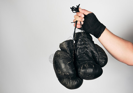 男用黑色弹运动绷带包着男手臂上面有两对旧式皮拳击手套灰色背景复制空间图片