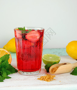 白色木板上杯子中的红草莓柠檬黄色在后面图片
