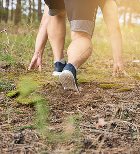 身穿蓝衣服和黑短裤的成年男子在阴险的森林中奔跑对抗明亮的太阳健康生活方式的概念和在新鲜空气中奔跑背景图片