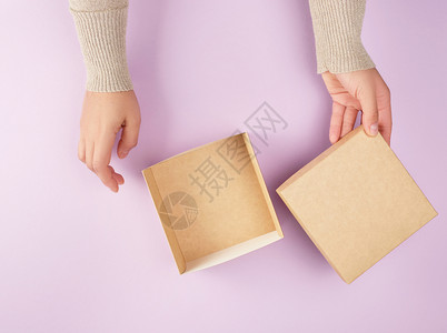 女孩打开一个棕色方盒子紫背景最高视野赠送礼物的概念图片
