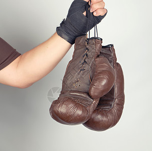 男用黑色弹运动绷带包着男手臂用灰色旧式皮拳击手套包着一对旧式皮革手套图片