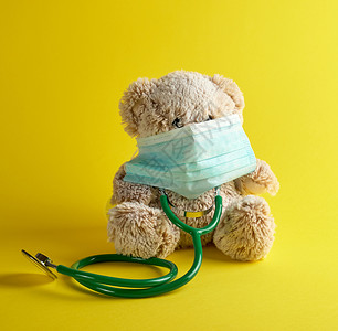 灰色泰迪熊和黄背景的绿医学听诊器儿童治疗概念背景