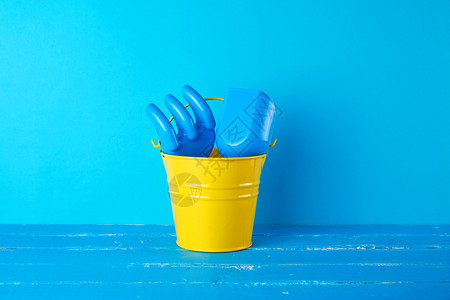 黄色儿童金属桶塑料铲子和蓝背景的摇篮海上假日概念图片