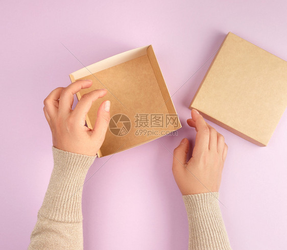 女孩打开一个棕色方盒子紫背景最高视野赠送礼物的概念图片