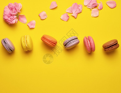 甜多色玉子奶油和粉红玫瑰芽花瓣散落于黄色背景顶视平面复制空间图片